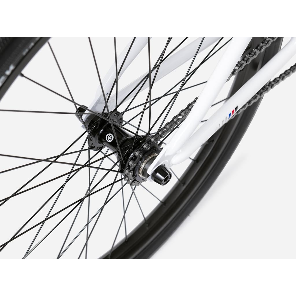 Close-up of the rear wheel on a Wethepeople Atlas 24 Inch Bike, featuring hub, black spokes, chain, and part of the frame with 24" wheels against a white background.