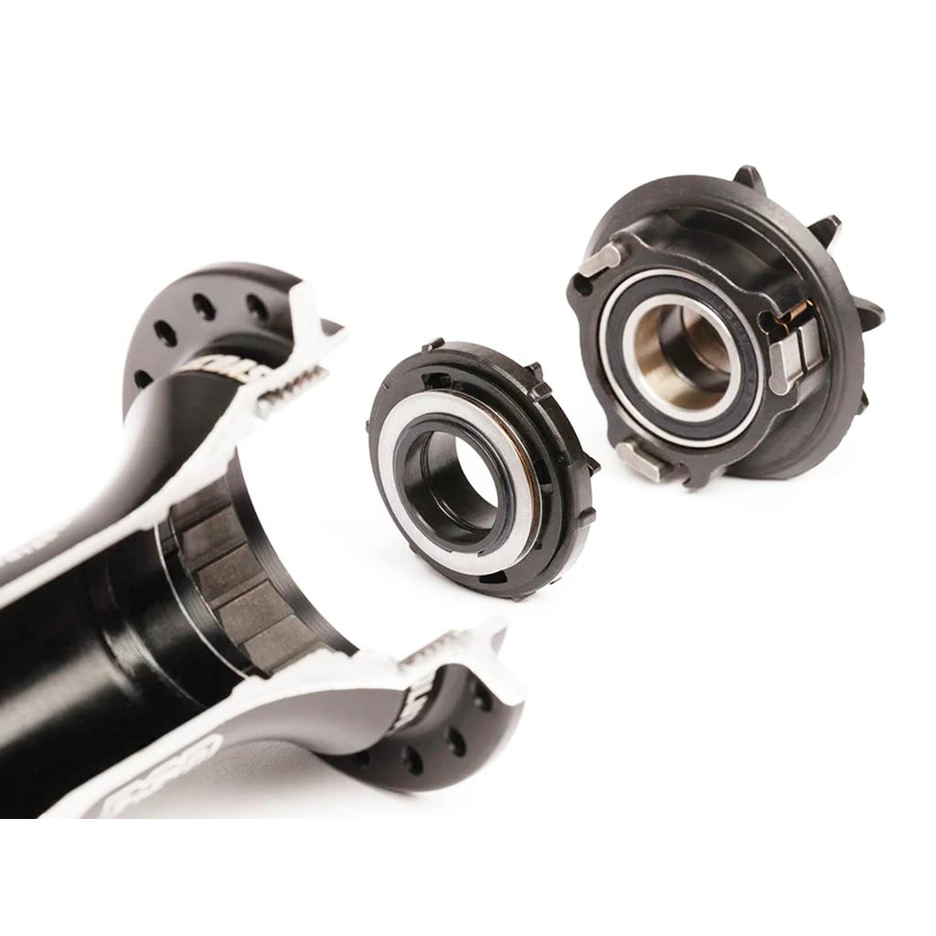 Cross-section of a bicycle bottom bracket and its internal bearings, separated on a white background, similar to how the BSD Revolution V1.5 Freecoaster Hub (Male Axle) displays its planetary clutch mechanism for smooth engagement.