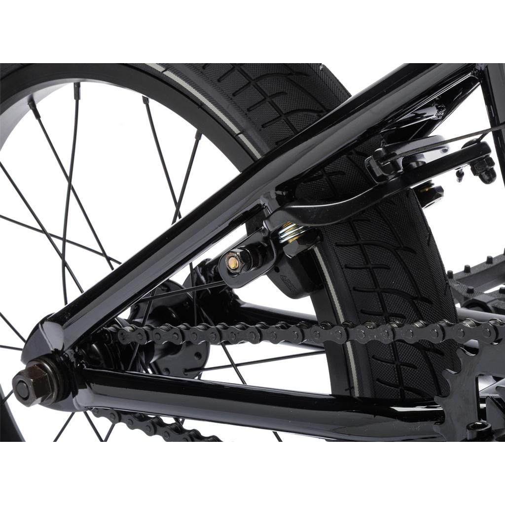 Close-up of a black Fit Bike Co Misfit 16's rear wheel, showing the tire, chain, frame, and part of the brake mechanism.