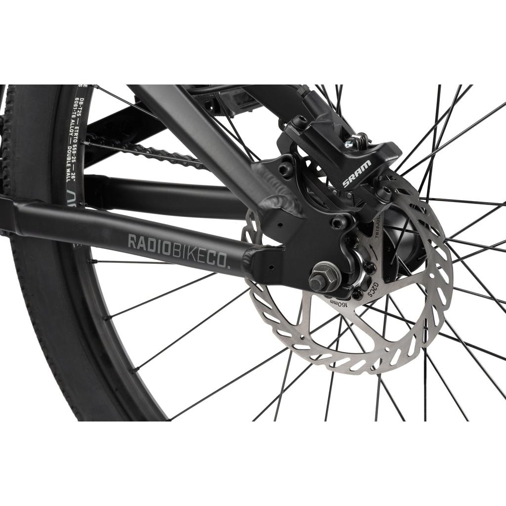 Close-up of the Radio 26 Inch Griffin Pro Bike's rear wheel, featuring a disc brake rotor, SRAM-branded caliper, and an alloy frame labeled "RADIOBIKECO.