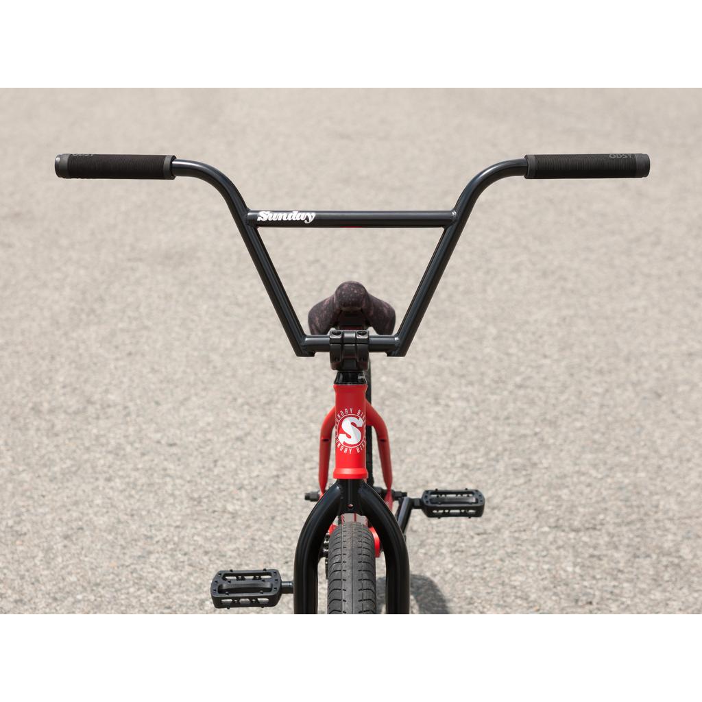 Front view of a red Sunday Forecaster 20 Inch Bike (2025) / Brett Silva, pro-level BMX with black handlebars and pedals, 100% chromoly frame, shown on a paved surface.