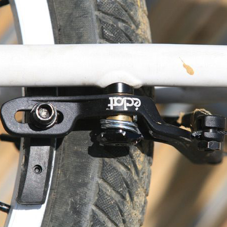 Close-up of a bicycle's brake system showing a white frame, black Eclat The Unit Brake, and the tire.