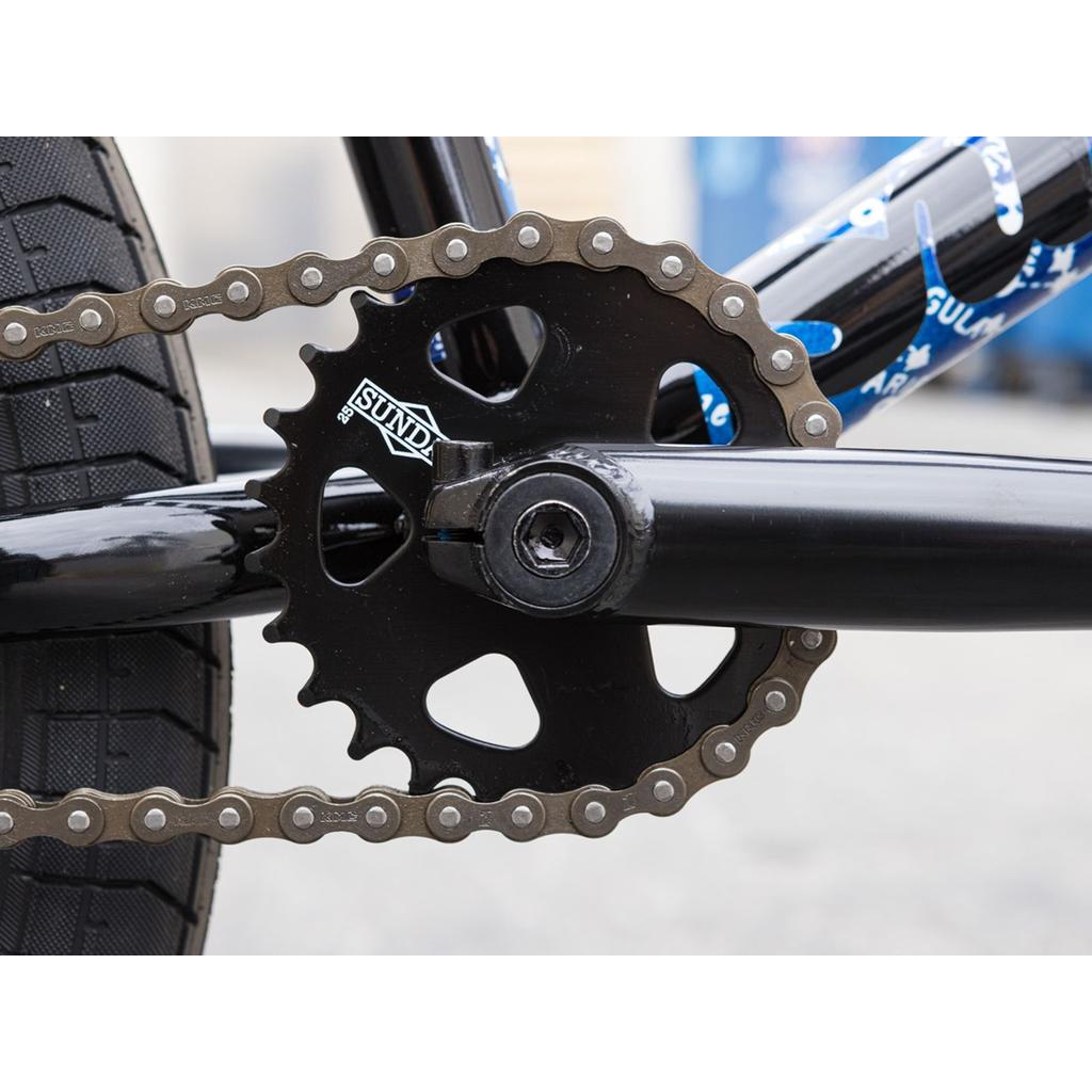 Close-up of a Sunday Forecaster Maca Grasset 20 Inch Bike crankset, featuring the chainring labeled "Sunday," along with the chain and part of the rear tire.