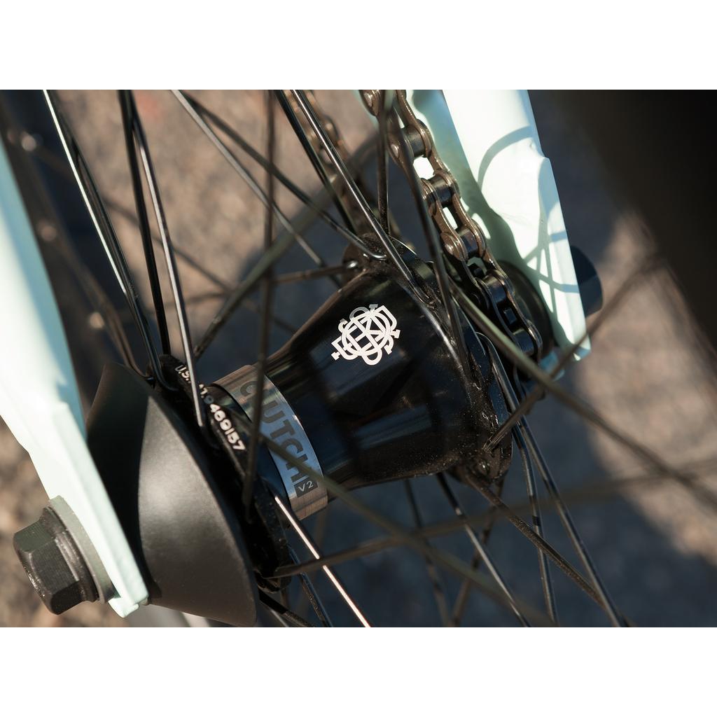 Close-up of the Sunday EX Julian Arteaga 20 Inch Bike’s rear wheel hub with black spokes, white geometric logo, visible chain, and a 100% chromoly frame.