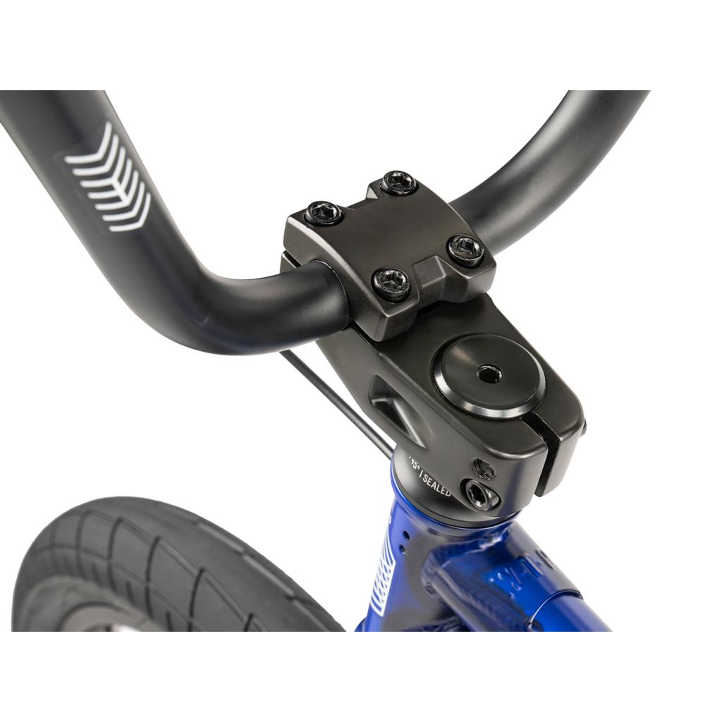 Close-up of the black handlebar and stem on a Wethepeople CRS FC 20 Inch Bike's blue frame, with part of the front tire visible.