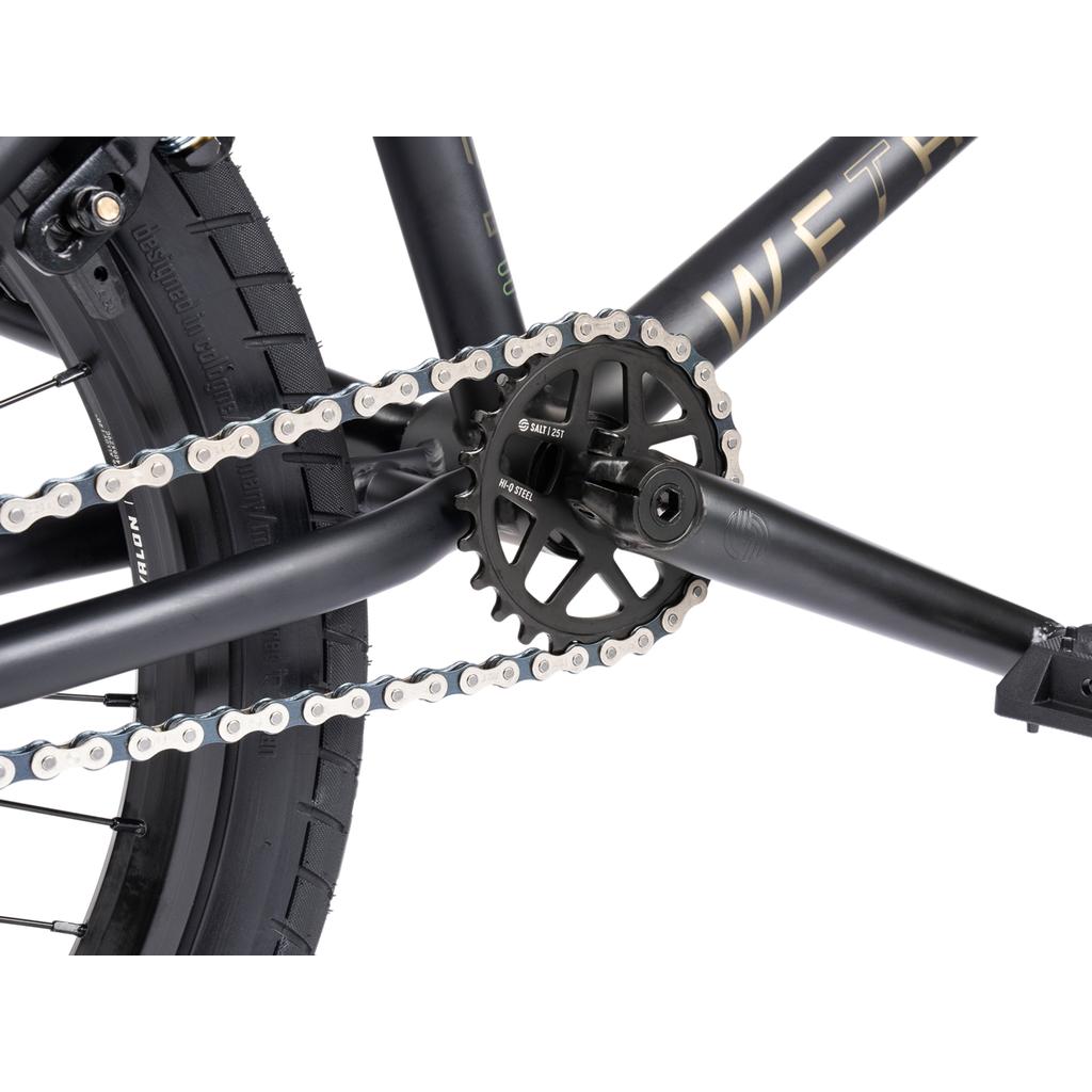 Close-up of the Wethepeople Arcade 20 Inch Bike’s rear wheel, chain, and black crankset with a 25-tooth sprocket and Salt Valon Rims, highlighting the visible tire tread.