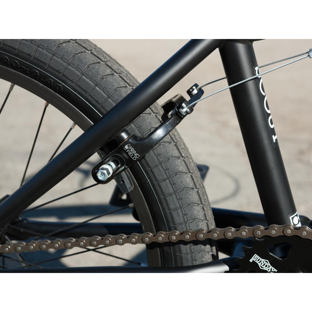 Close-up of the Sunday Scout 20 Inch Bike's rear wheel, showcasing the tire, chain, chromoly frame, and Odyssey brake caliper connected by a cable.