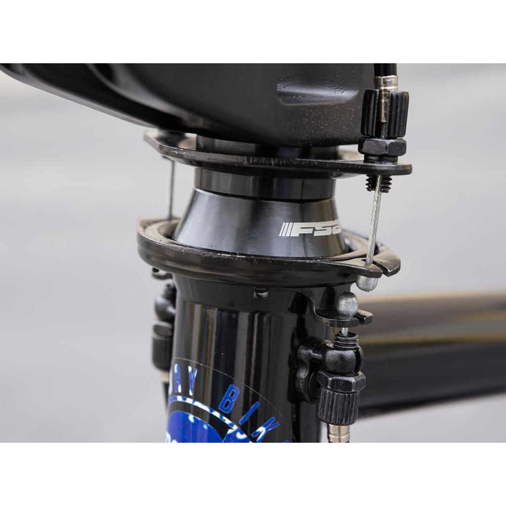 Close-up of the Sunday Forecaster Maca Grasset 20 Inch Bike's BMX headset and brake assembly, showing the FSA logo, gyro setup, brake cables, and bolts on its black park frame.