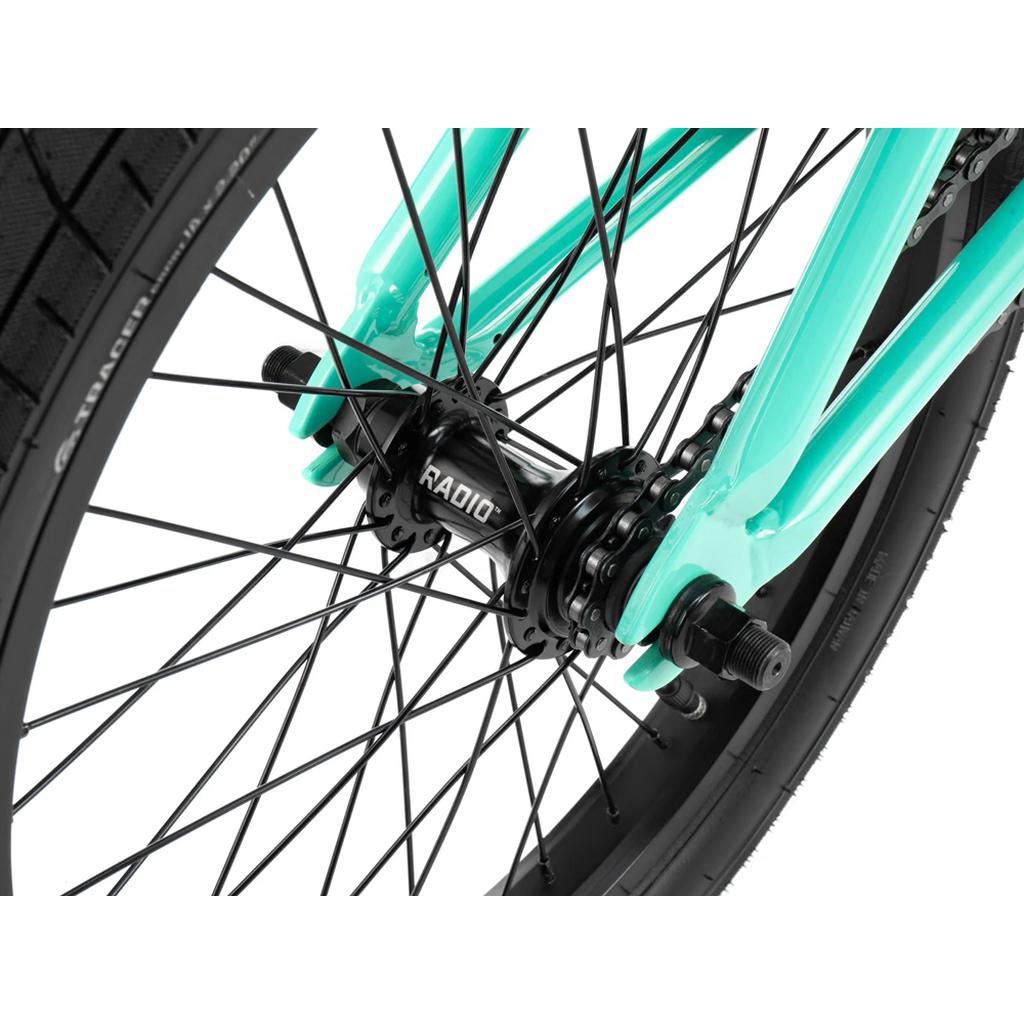 Close-up of the rear wheel on the Radio Saiko 18 Inch Bike, featuring a black "RADIO" hub, spokes, Salt Tracer Tyres, and a mint green frame.