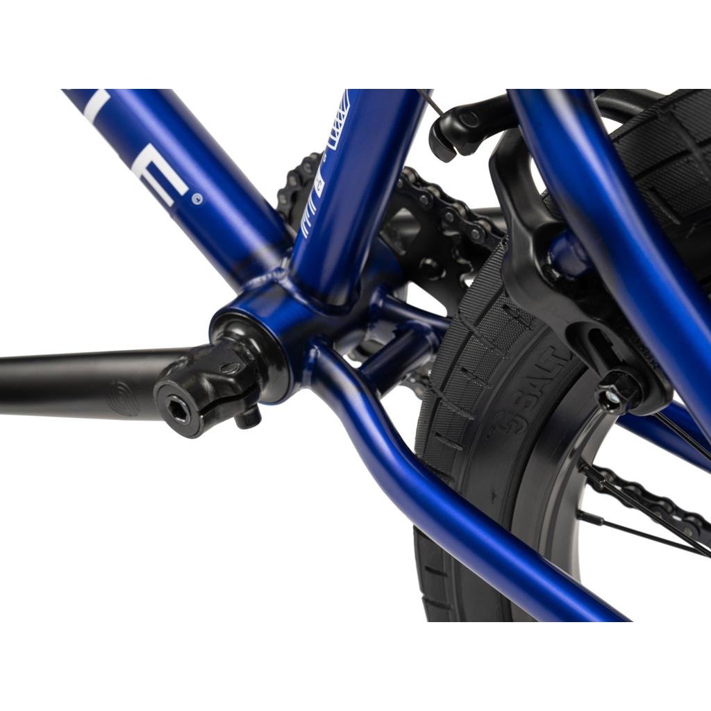 Close-up view of the Wethepeople CRS FC 20 Inch Bike's blue frame, highlighting the crank area, rear tire, and part of the braking mechanism.
