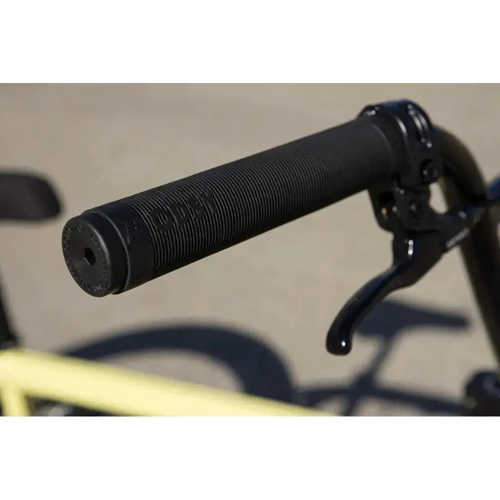 Close-up of a black handlebar grip with "ODSY" branding and brake lever, featuring quality Odyssey parts on the Sunday Soundwave Special Bike (2025). The background is out of focus.