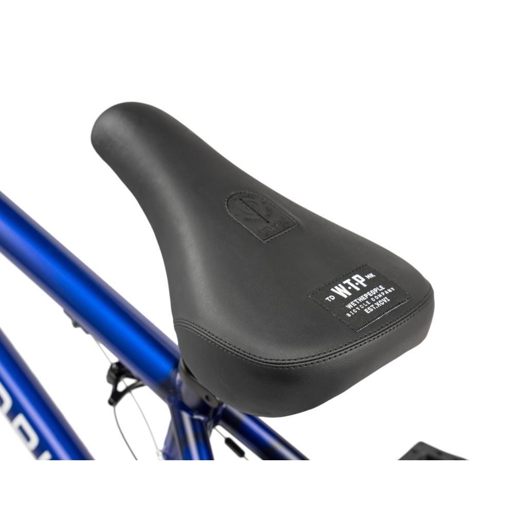 Close-up of a black BMX bike seat with white text on the back, attached to the blue frame of the Wethepeople CRS FC 20 Inch Bike—ideal for beginners.