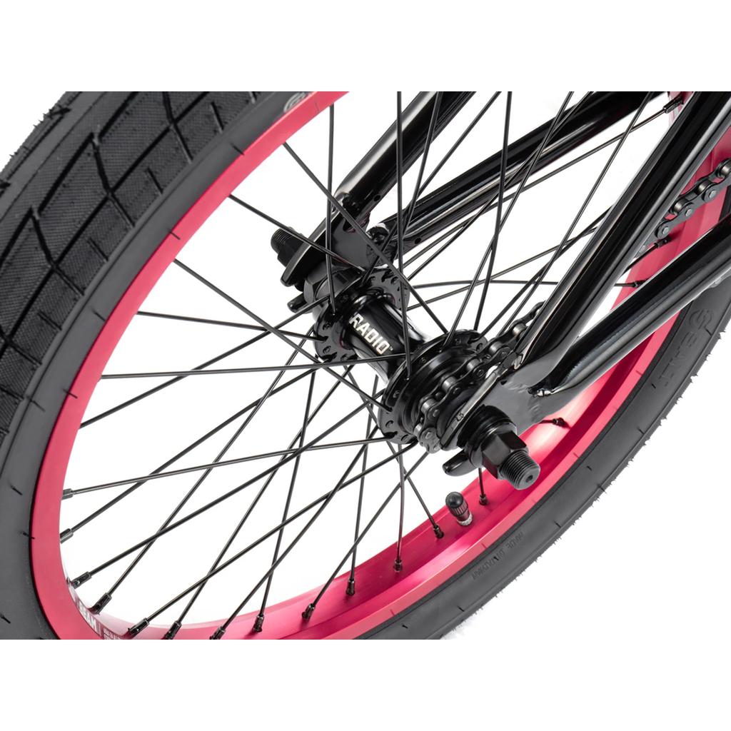 Close-up of the Radio Saiko 18 Inch Bike’s rear wheel, featuring a black RADIO-labeled hub, black spokes, red rim, and Salt Tracer Tyres against a white background.