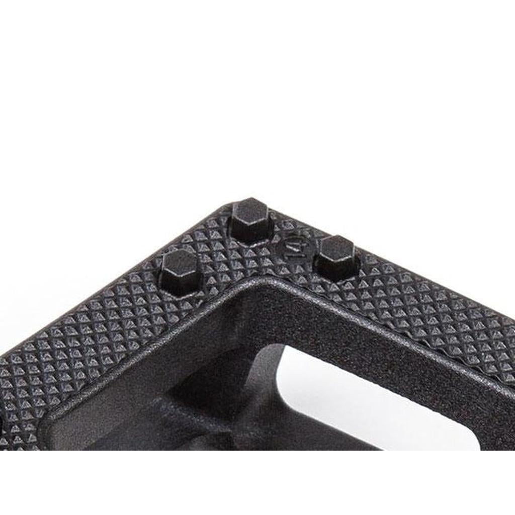 Close-up of the BSD Safari PC Pedals—black, textured, with three hexagonal bolts—showcasing their rugged design against a white background.