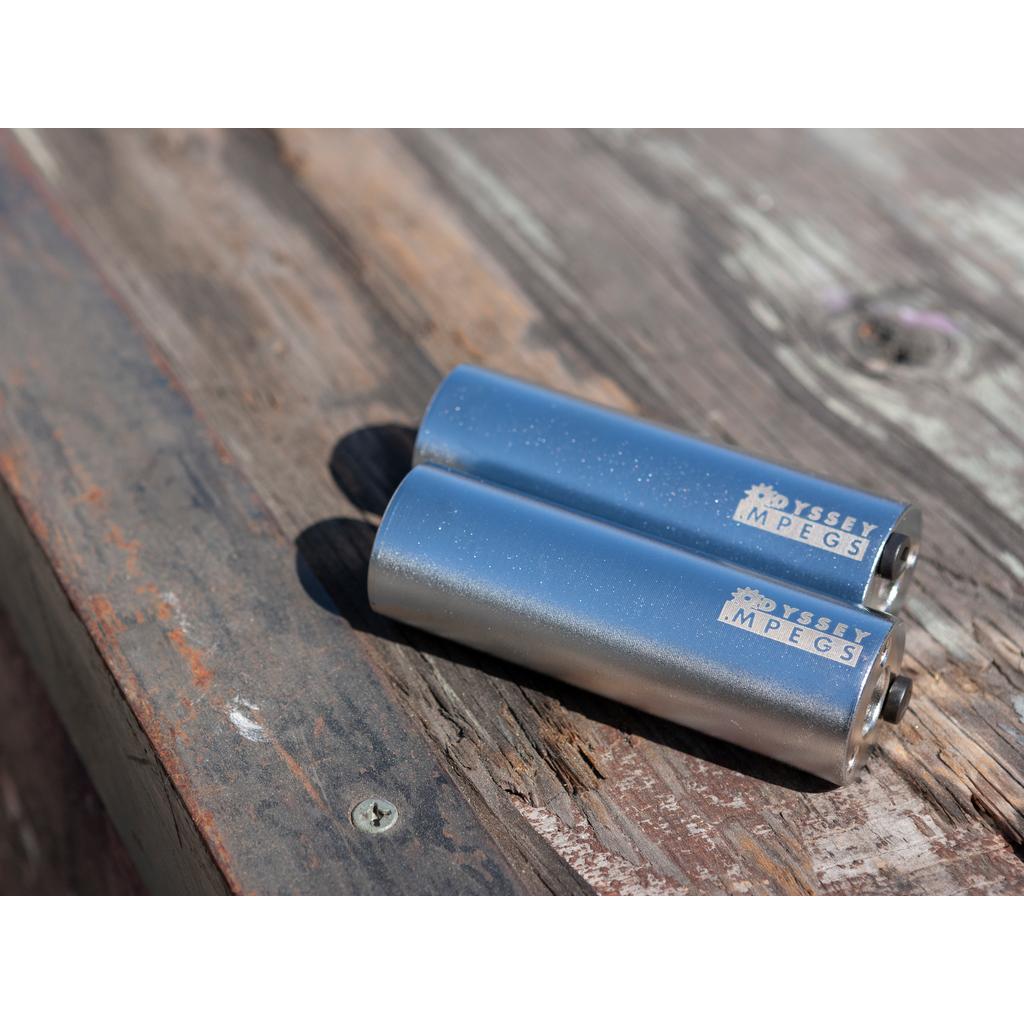 A pair of Odyssey MPEG Pegs rests side by side on a weathered wooden surface.