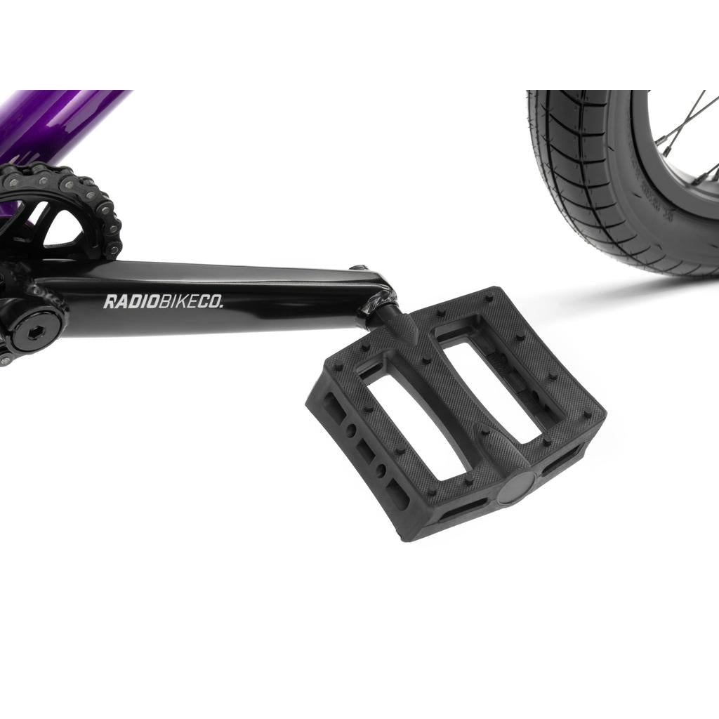 Close-up of a black pedal and crank arm with "RADIOBIKECO." branding on the Radio Darko 20 Inch Bike, showing its BMX wheel, chainring, and Salt Burn Tyres.