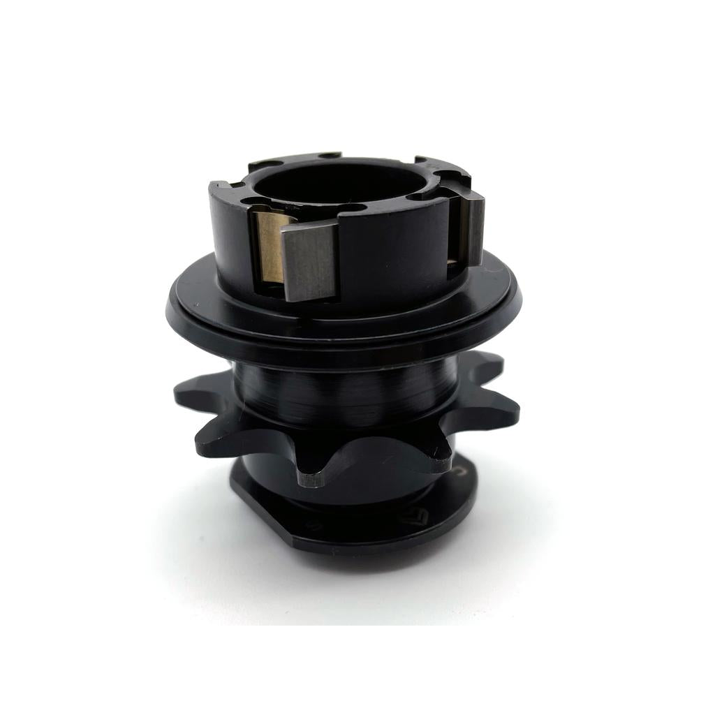 The Eclat Cortex CS Cassette Hub Driver is a black, cylindrical metal component with gear-like teeth and metal inserts, shown against a white background.