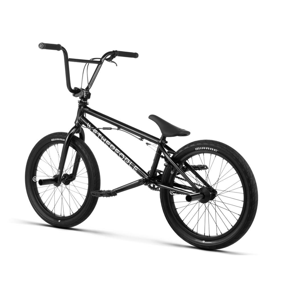 The Wethepeople Versus 20 Inch Bike in black features thick tires, a padded seat, wide handlebars, and pegs on both wheels, displayed against a white background—ideal for skatepark riders wanting durability and style.