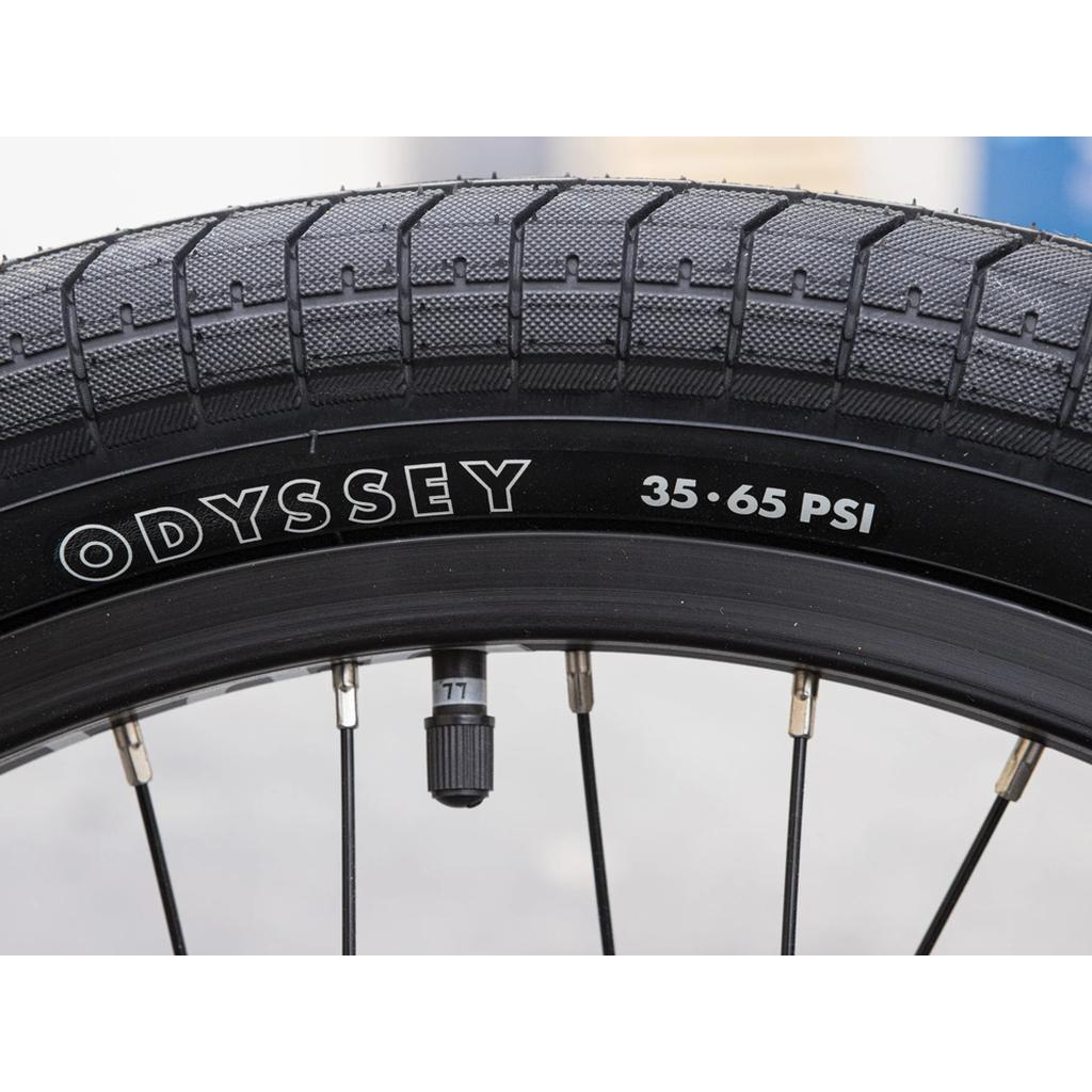 Close-up of the Sunday Forecaster 20 Inch Bike tire, showing Odyssey parts, a visible valve stem and spokes, and the recommended pressure range of 35-65 PSI.