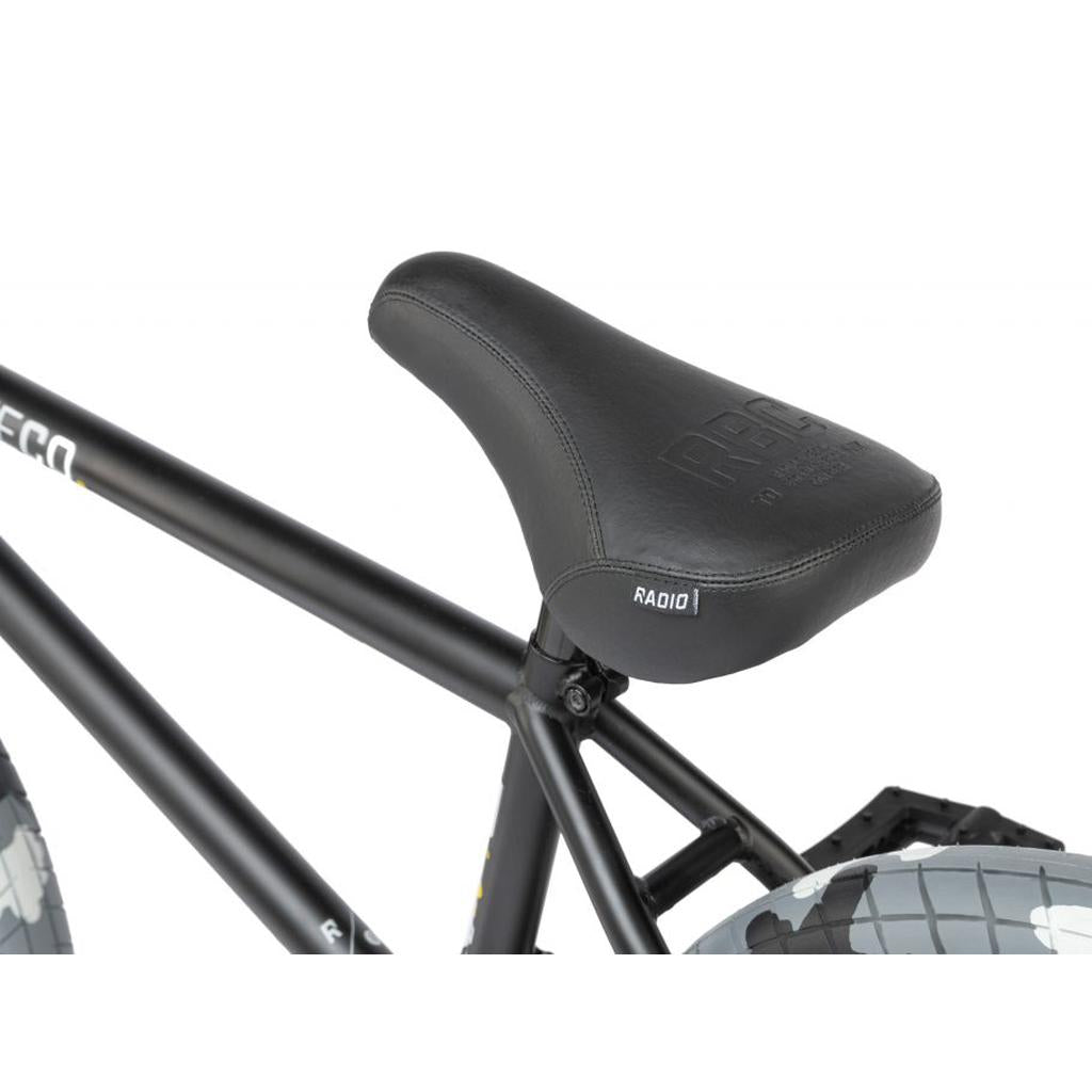 Close-up of a black bicycle saddle on the Radio Darko 20 Inch Bike, featuring a matte black Chromoly frame and Salt Burn Tyres, with part of the rear tire visible in the background.
