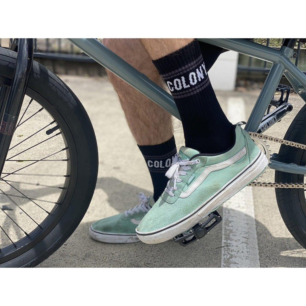 A man riding a bike with comfortable, Australian made green Colony BMX Logo Socks.