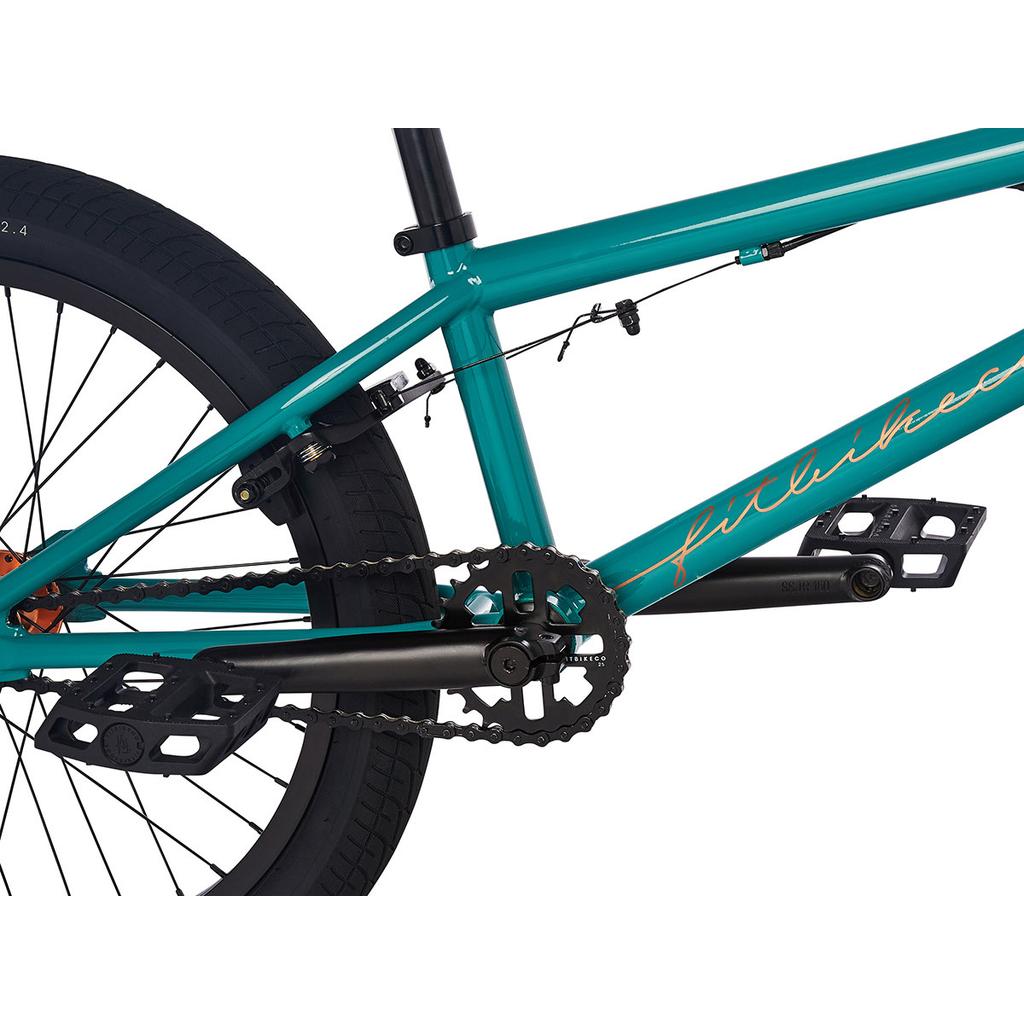 Close-up of the drivetrain on a teal Fit Prk 20 Inch Bike (2023), showing the chain, pedals, crankset with sealed bearings, rear wheel, and brake cable.