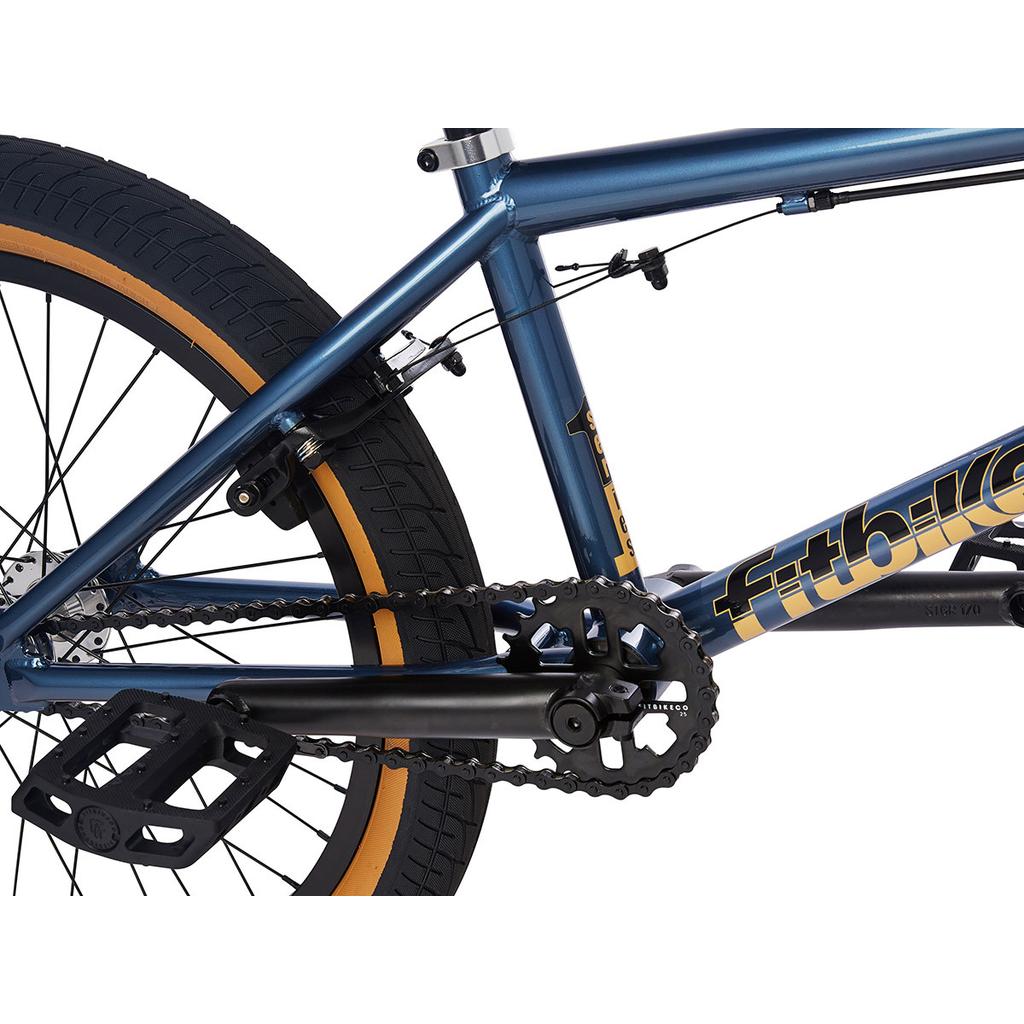 Close-up view of the 2023 Fit Series One 20 Inch Bike frame, highlighting the rear wheel, chain, pedals, crankset, brake cables, and a tan sidewall tire.