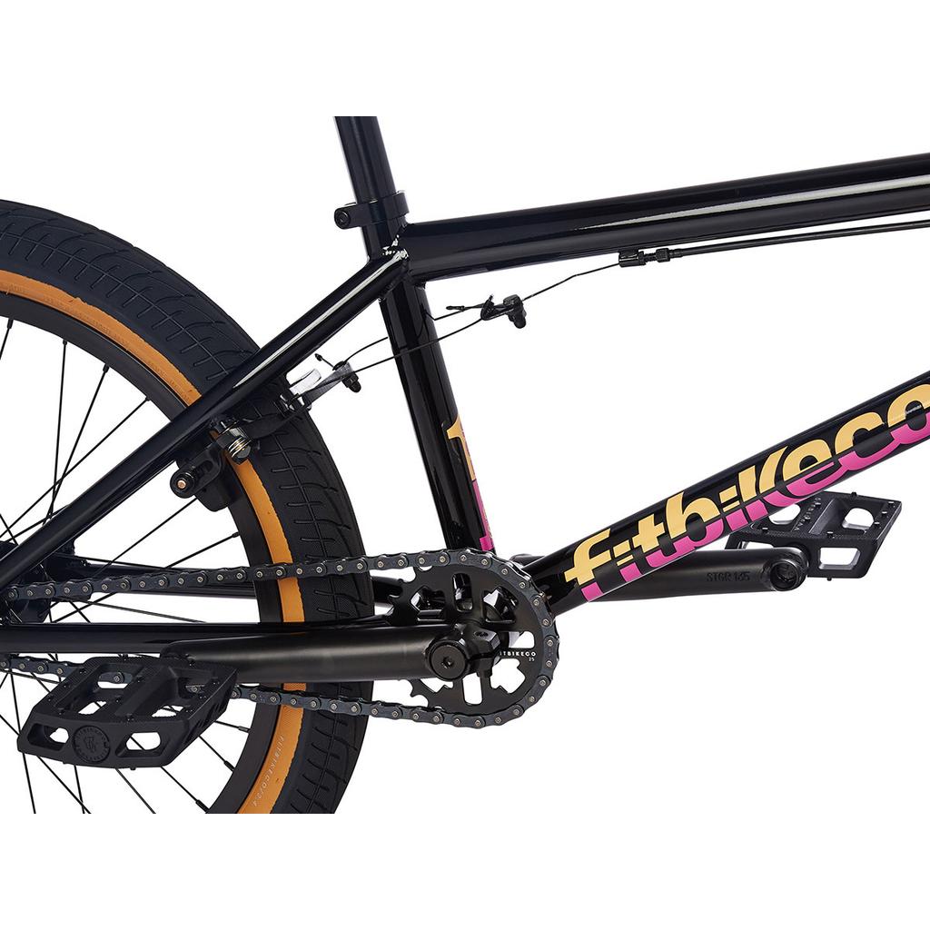 Close-up of the Fit Series One 20 Inch Bike (2023), entry-level BMX in black, featuring the chain, pedals, rear tire, and "fitbikeco." branding.