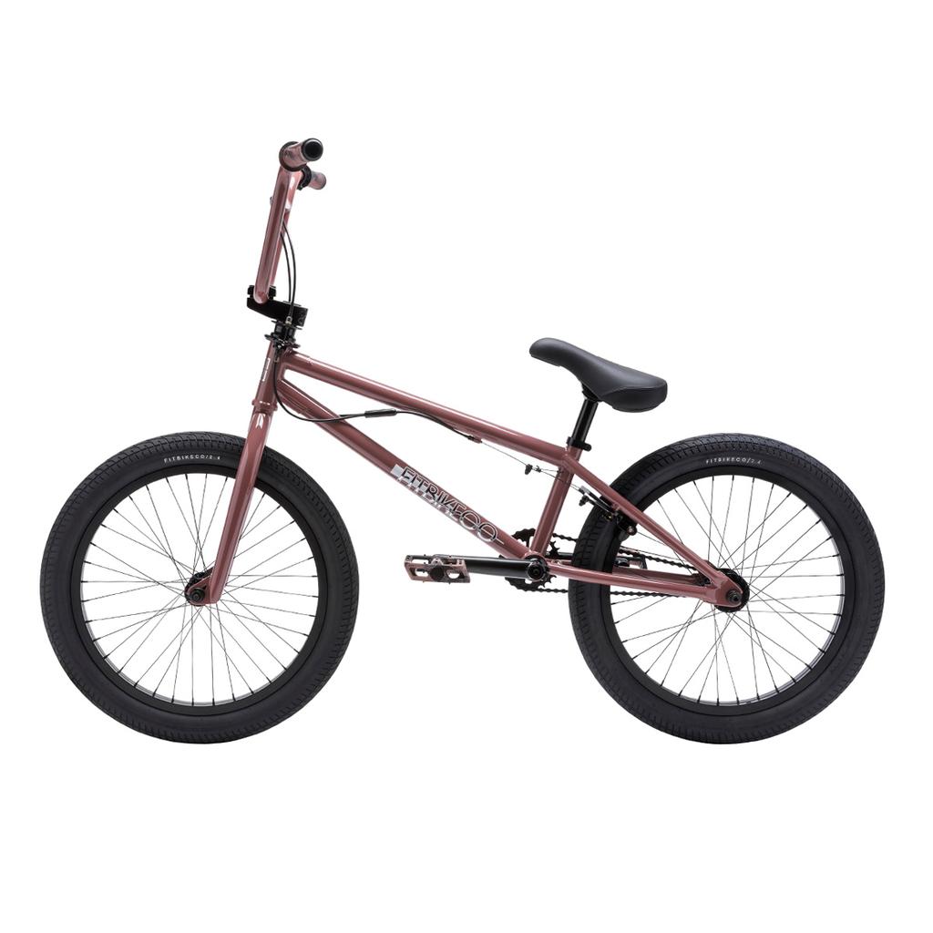 The Fit Bike Co PRK 20 Inch Bike is a matte red BMX park bike with a short top tube, black tires, black seat, and silver pedals, shown in profile view against a white background.