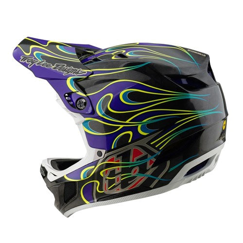 The TLD 25.1 D4 Carbon Helmet (MIPS) in Torched Black/Purple showcases a striking flame design in purple, yellow, and blue on a sleek black base. Crafted from carbon fiber, it offers enhanced durability and Mips Protection for ultimate safety.