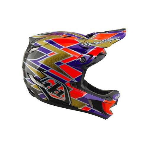 Introducing the TLD 26.2 D4 Carbon Full Face Helmet / MIPS Flush Violet—a downhill mountain bike helmet featuring a black base with gold, red, and purple geometric patterns. With “Troy Lee Designs” proudly displayed on the visor and advanced MIPS protection integrated for enhanced trail safety, this helmet delivers both standout style and top-tier performance.