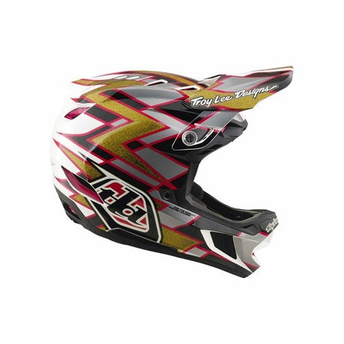 Introducing the TLD 26.2 D4 Composite Helmet / MIPS Flush Black: a full-face motocross helmet featuring striking red, gold, black, and white geometric graphics with “Troy Lee Designs” text on the visor. Equipped with advanced MIPS protection, this helmet offers enhanced safety out on the trail.