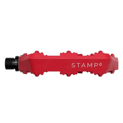 The Crank Brothers Stamp 0 Pedals (Small) are red flat composite pedals with "STAMP" branding and a black axle, shown in side profile on a white background for maximum grip.