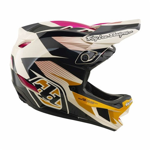The TLD D4 Polyacrylite Helmet in the Turbo Acid/Fuchsia colorway features a bold black, white, pink, and yellow geometric design with Mips brain protection for enhanced safety, plus the iconic Troy Lee Designs logo on the visor and chin guard—making it a top choice for mountain biking adventures.