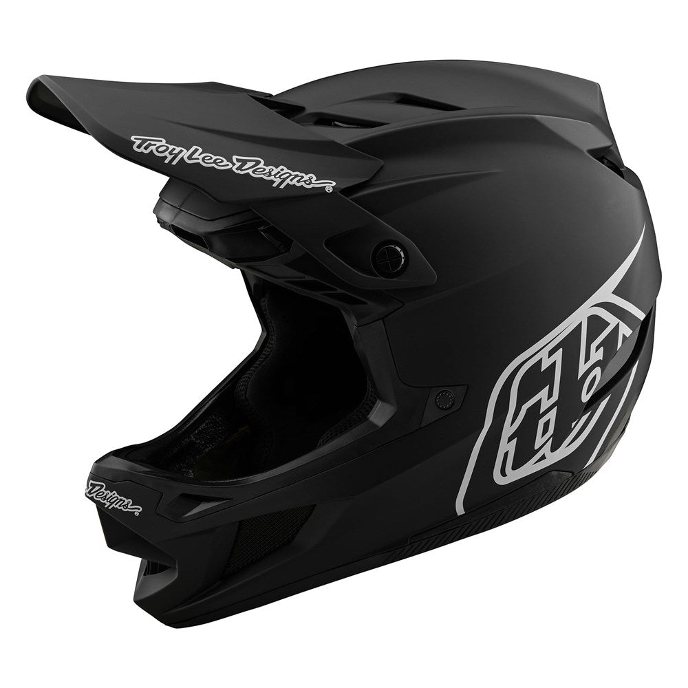The TLD D4 AS Polyacrylite Helmet W/MIPS Stealth Black is a matte black full-face helmet with a visor, white Troy Lee Designs branding, and geometric graphics on the side and chin.
