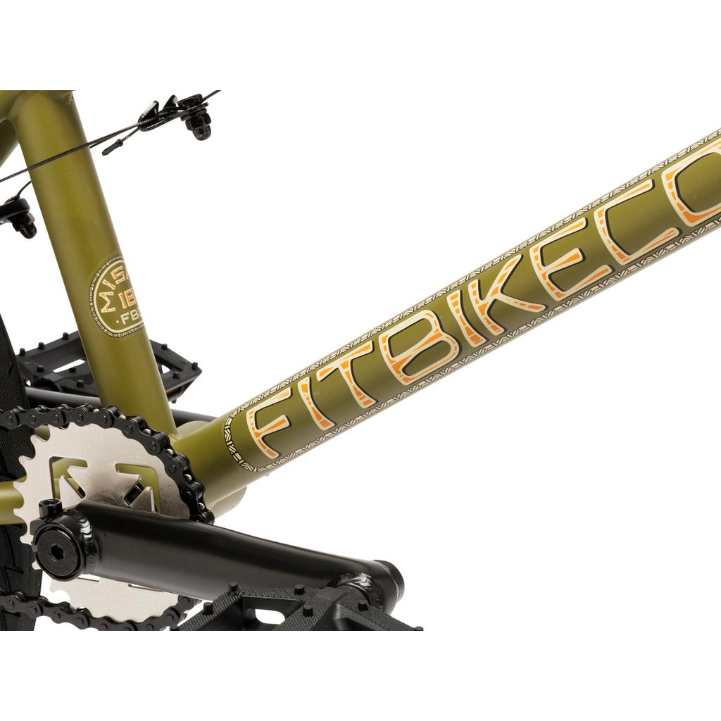 Close-up of the green Fit Bike Co Misfit 18 Inch Bike frame showing the "FITBIKECO." logo, crankset, pedals, and part of the chain—ideal for young BMX riders.