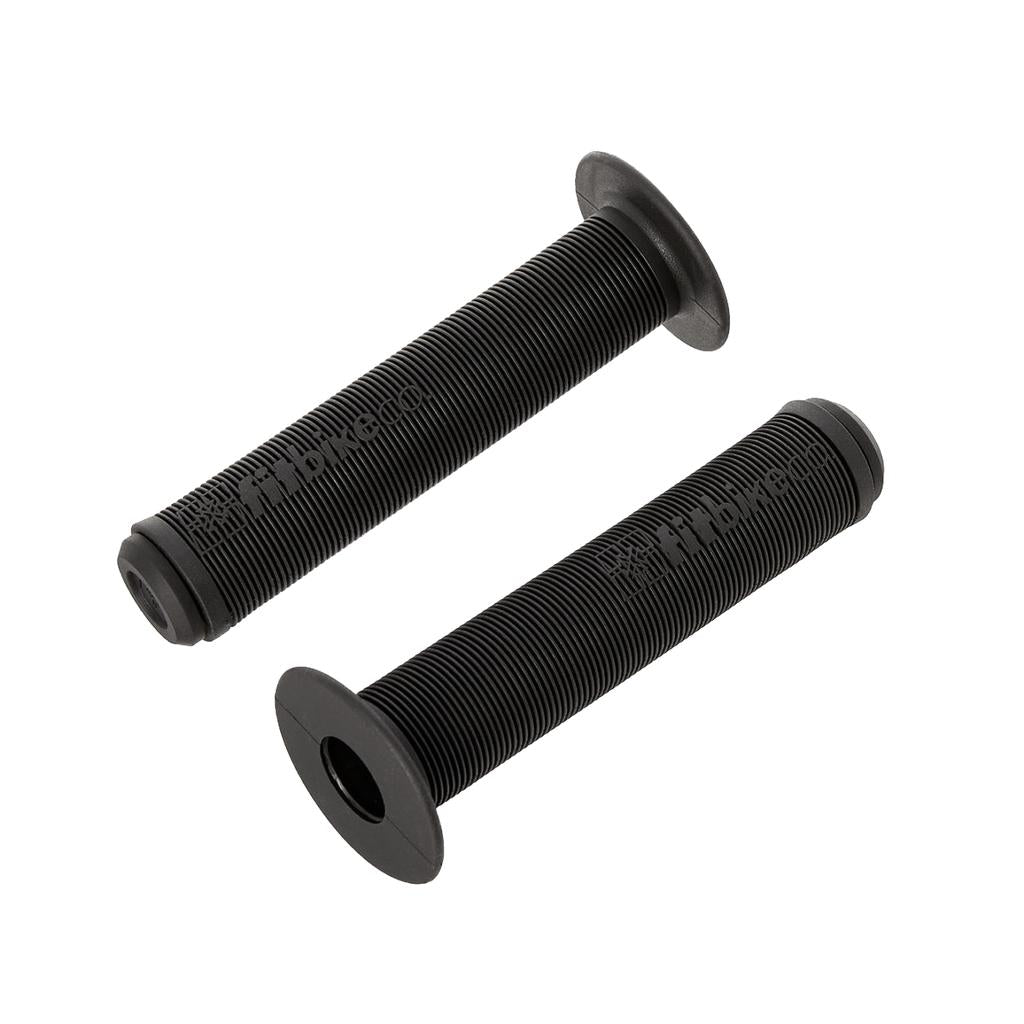 The Fit Bike Co OG Grips, shown in black with ribbed and mushroom-finned surfaces plus flared ends, resemble the classic BMX grip style and are displayed on a white background.