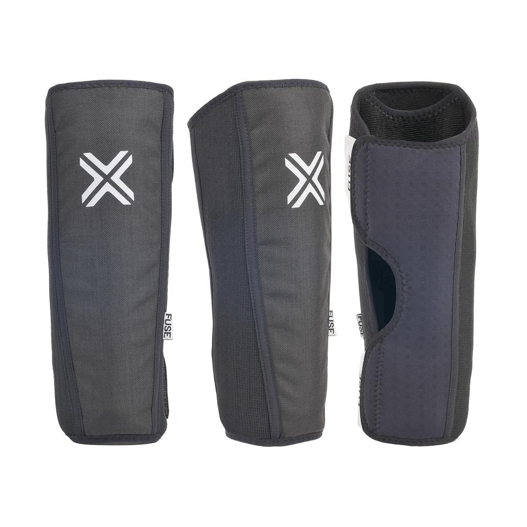 Three black Fuse Alpha Shin Pads (Pair) with white "X" logos and perforated inner lining are shown from the front, side, and back.