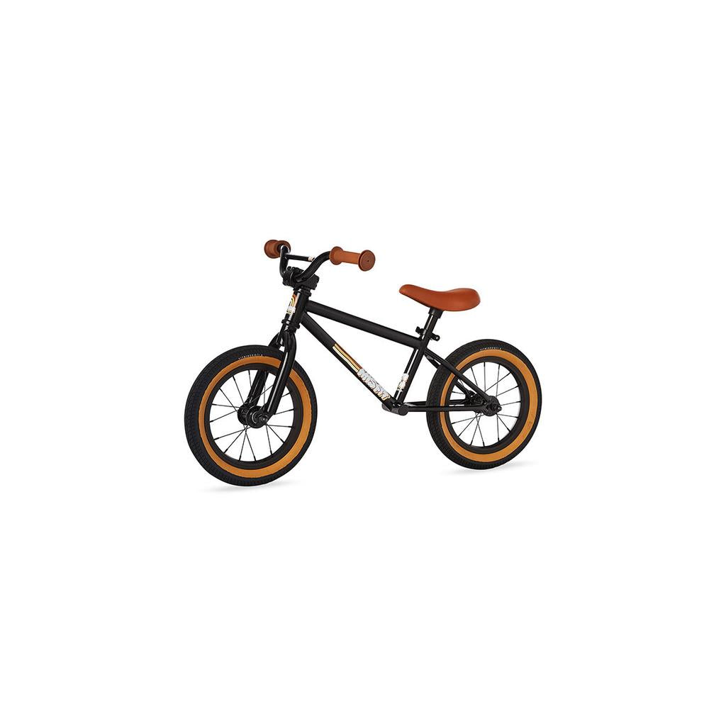 The Fit Misfit 12 Inch Balance Bike is a small black BMX-style kids' bike with brown seat, grips, and tires—ideal as a balance bike for young riders. Shown on a white background.