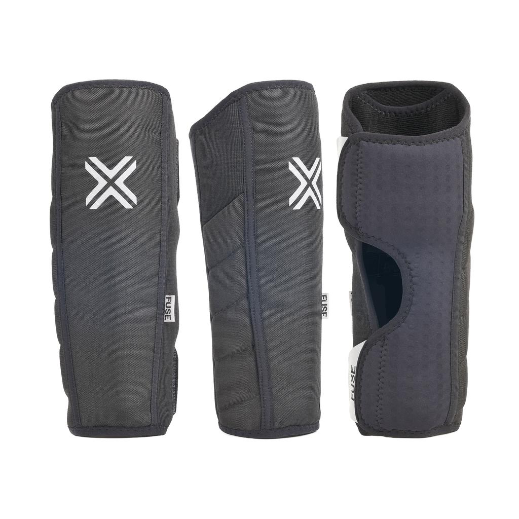 Three Fuse Alpha Shin Whip Pads (Pair) in black with white X logos and side tags, displayed from front, side, and back. One reveals an open section, highlighting the whip pad leg protection and inner padding.