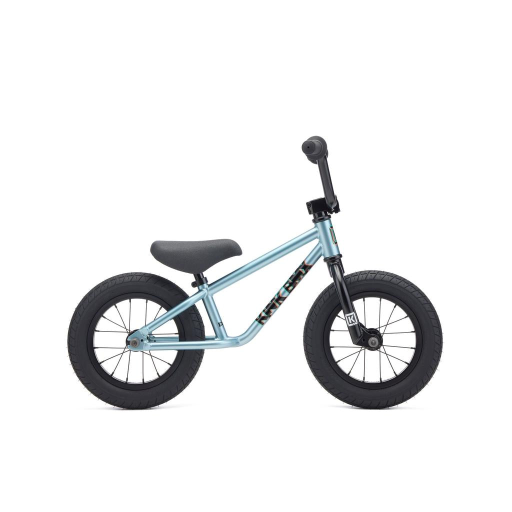 The Kink Coast 12 Inch Balance Bike (2027) is a small, light blue bike with 12-inch tyres, black wheels, seat, and handlebars, shown in side view on a white background.