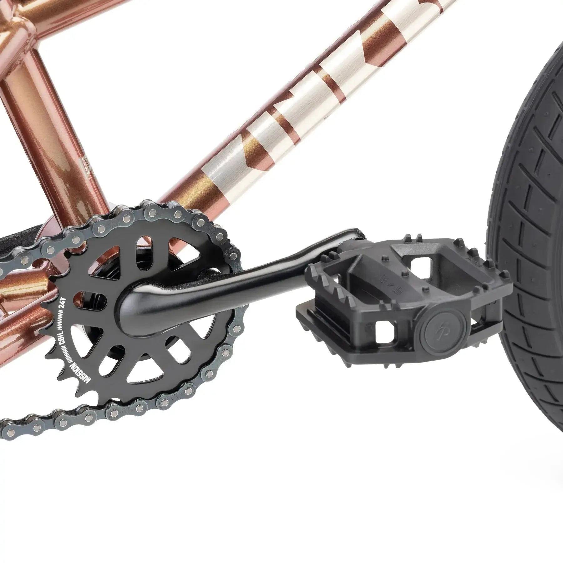 Close-up view of the Kink Roaster 12 Inch Bike (2026) showing its crankset, chainring, and black plastic pedal on a metallic frame with coaster brake and rear tire.