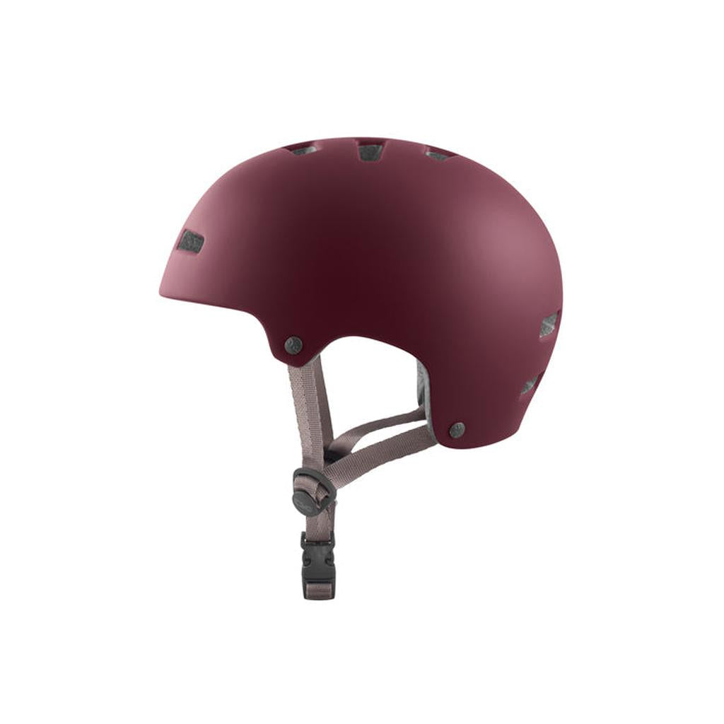 A TSG Nipper Maxi Helmet in Satin Cabernet, featuring ventilation holes, side straps, In-Mold Construction, and a black buckle, shown in a left side profile view.
