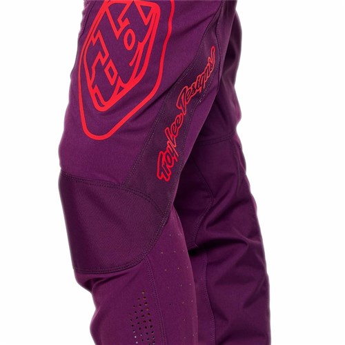 Close-up of a person wearing TLD 26.1 Sprint Pro Pants / Mono Sangria—purple riding pants with red graphics, made from durable 4-way stretch fabric for comfort and performance.