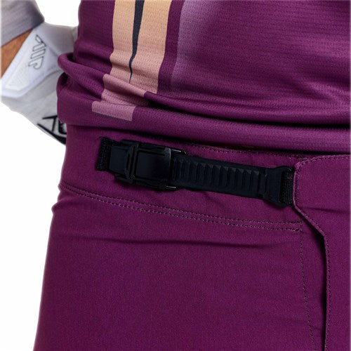 Close-up of a person wearing TLD 26.1 Sprint Pro Pants / Mono Sangria, showcasing a black adjustable waistband buckle and durable 4-way stretch fabric.