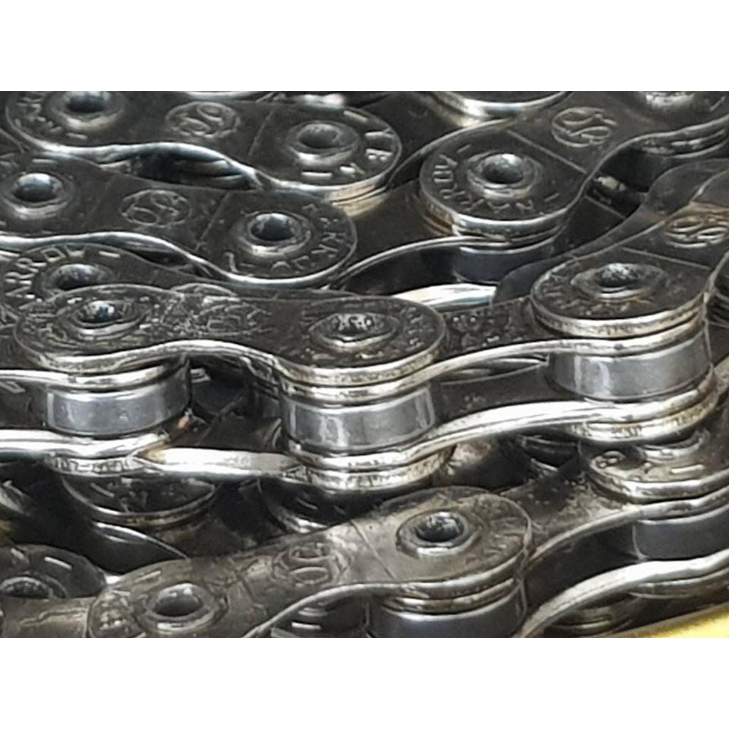 Close-up of interlocking MCS Superlight Chain (1/2 x 3/32 Inch) links, emphasizing the rivets and worn surfaces of this lightweight BMX bike chain.