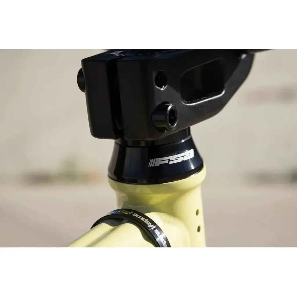 Close-up of a bicycle headset and stem with the FSA logo, part of the yellow frame on the Sunday Soundwave Special Bike (2025), built with quality Odyssey parts and backed by a 41-Thermal Lifetime Warranty.