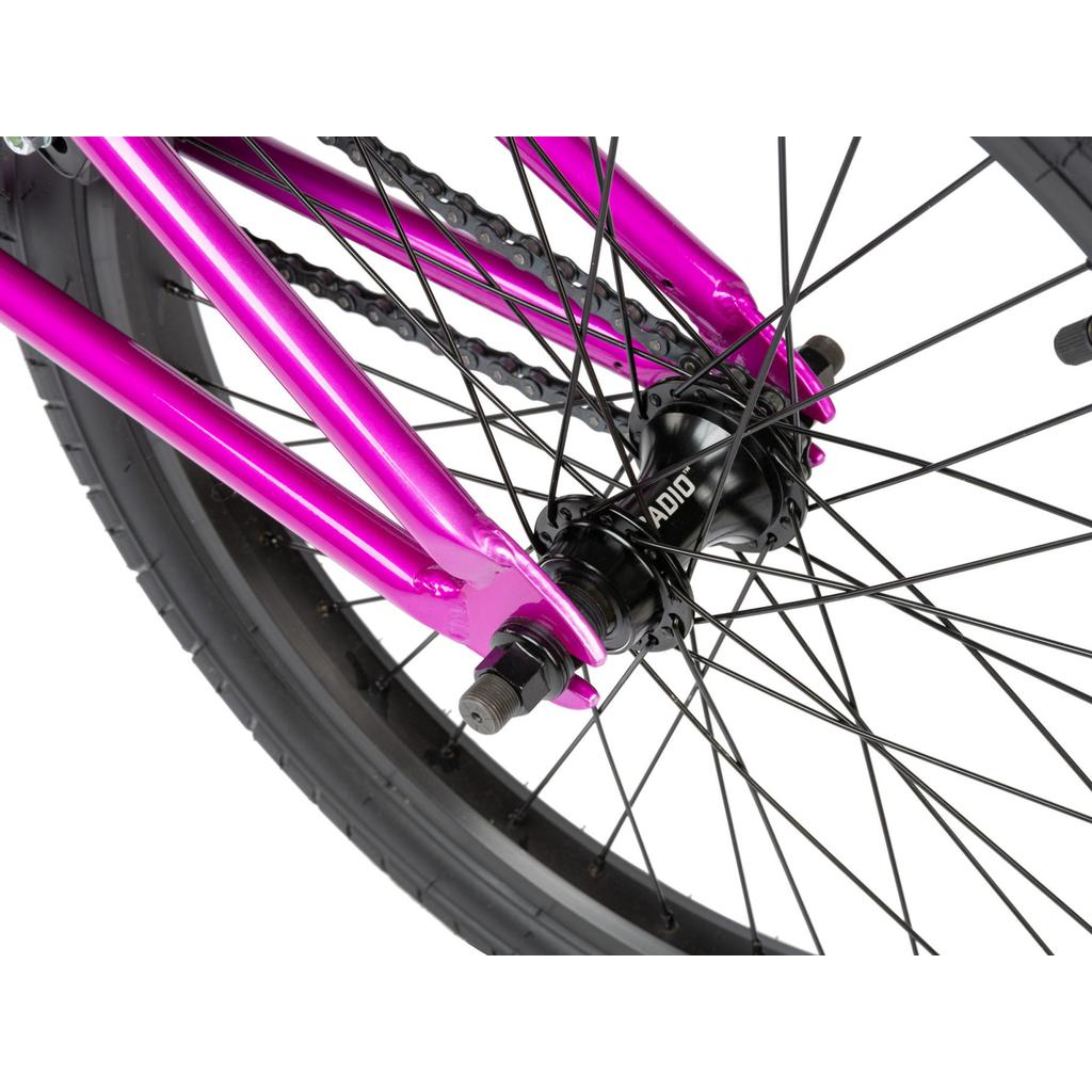 Close-up of the Radio Saiko 20 Inch Bike’s rear wheel, showing its pink frame, black spokes and chain, Salt Tracer tyres, and a RADIO-labeled hub.