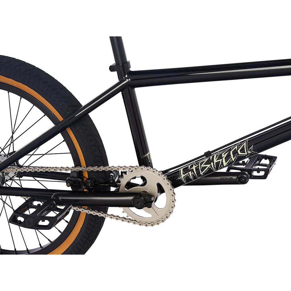 Close-up of a black Fit TRL Bike (2023) frame, showcasing the rear wheel, crankset, pedals, chain, and part of the frame with a gold graphic design.