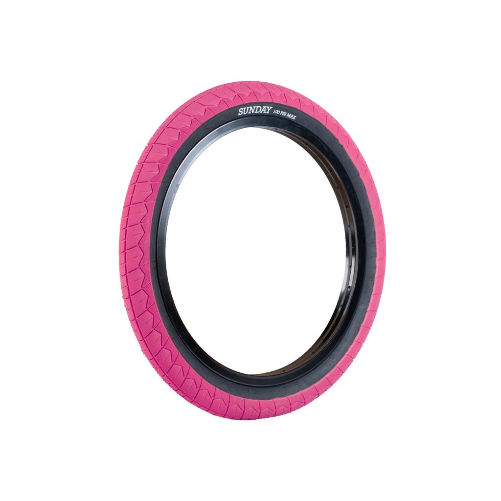 The Sunday Current V2 Tyre (Each) is a pink BMX tyre with a grippy tread and black sidewall, labeled "SUNDAY 100 PSI MAX," shown upright against a white background.